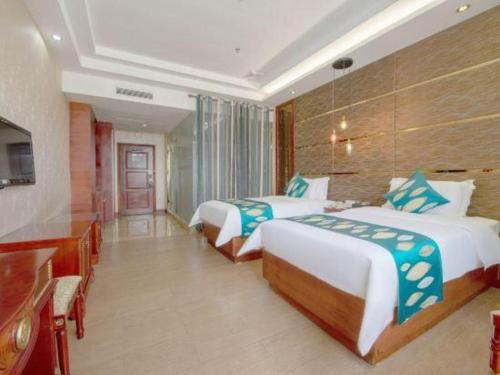 a hotel room with two beds and a television at Shenzhen Kai Long International Hotel in Shenzhen