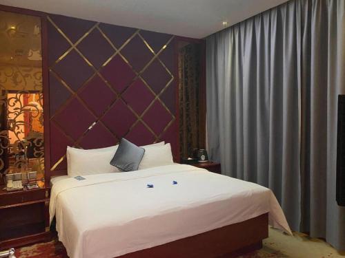 a bedroom with a large white bed with a purple wall at Shenzhen Kai Long International Hotel in Shenzhen