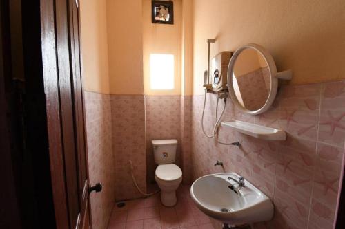 a bathroom with a toilet and a sink and a mirror at PXT Hotel in Ban Sivilai