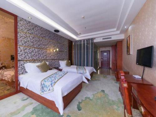 a hotel room with two beds and a flat screen tv at Shenzhen Kai Long International Hotel in Shenzhen