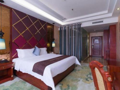 a bedroom with a large bed and a purple wall at Shenzhen Kai Long International Hotel in Shenzhen