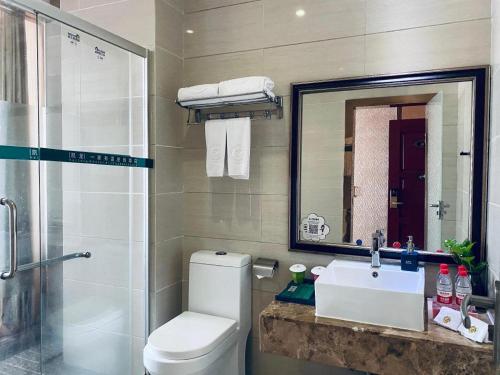 a bathroom with a toilet and a sink and a mirror at Shenzhen Kai Long International Hotel in Shenzhen