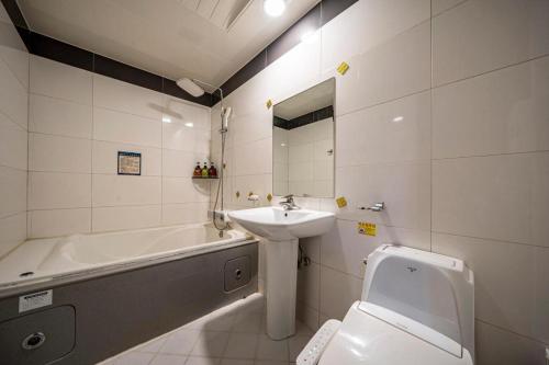 a bathroom with a sink and a tub and a toilet at SKY Hotel in Changwon
