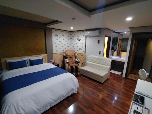 a bedroom with a large bed and a chair at SKY Hotel in Changwon