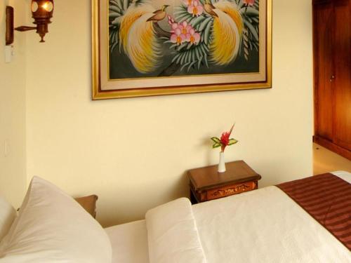 a bedroom with a white bed and a painting on the wall at Yusro Hotel Restaurant & Convention in Jombang