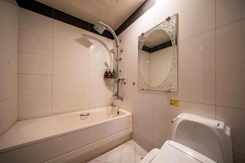 a bathroom with a tub and a toilet and a mirror at SKY Hotel in Changwon