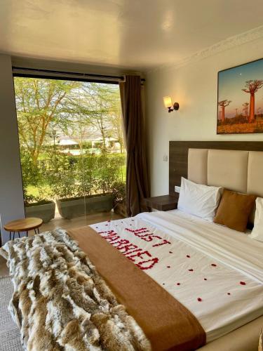 a bedroom with a large bed with a large window at Lake Elementaita Manor in Gilgil
