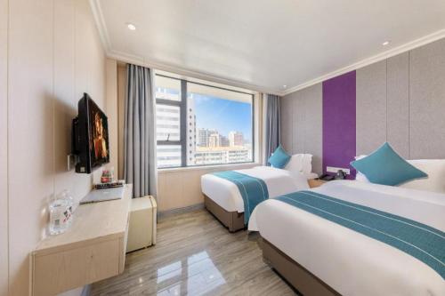 a hotel room with two beds and a tv at JIN HENG HUA YAN HOTEL in Guangzhou