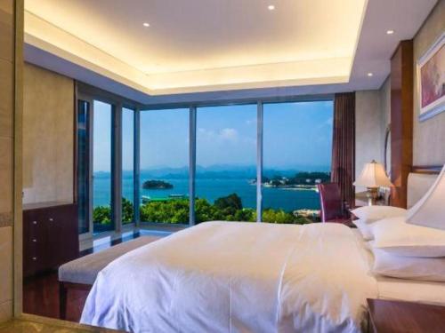 une chambre avec un grand lit et une grande fenêtre dans l'établissement Hangzhou 1000Island Lake Greentown Resort Hotel, à Lac Qiandao