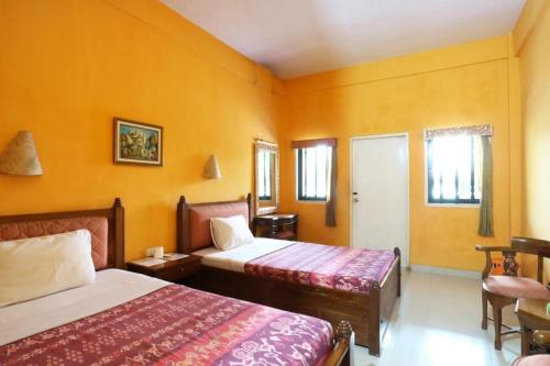 a hotel room with two beds and yellow walls at Sanur Ayu Hotel in Sanur