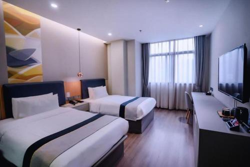 a hotel room with two beds and a flat screen tv at Home Inn Selected Xiamen University Zhongshan Road in Xiamen