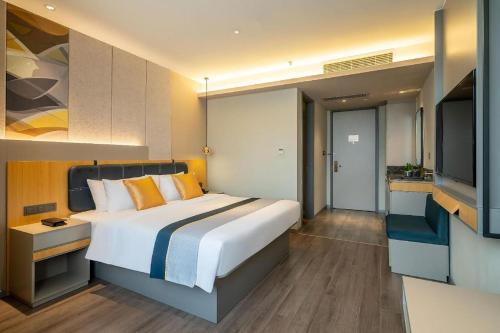 a bedroom with a large bed and a flat screen tv at Home Inn Selected Xiamen University Zhongshan Road in Xiamen