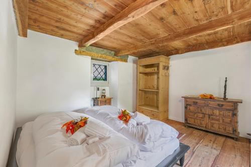a bedroom with a bed with white sheets and a wooden ceiling at Casa Kaia Verzasca - Happy Rentals in Gerra Verzasca