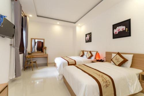 a hotel room with two beds and a television at Kim's Villa Hoi An in Hoi An