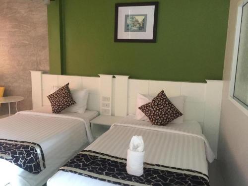 two beds in a room with green walls at Waenpetch place Hotel in Ubon Ratchathani