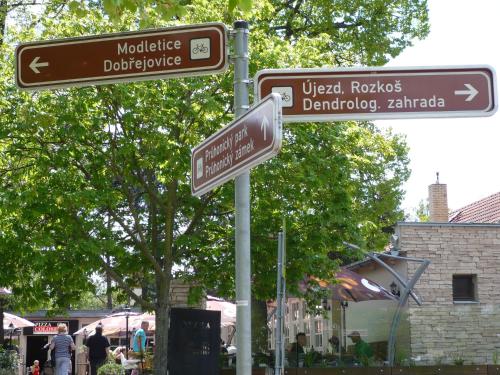 two street signs on a pole in a park at Rivendell Apartments in Prague