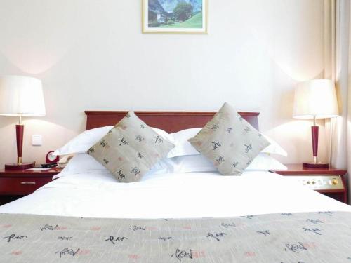a bedroom with a white bed with pillows and two lamps at Shaanxi Business Hotel in Shanghai