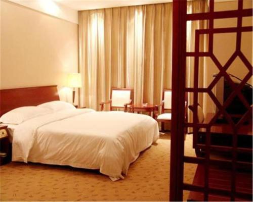 a hotel room with a white bed and a chair at Shaanxi Business Hotel in Shanghai