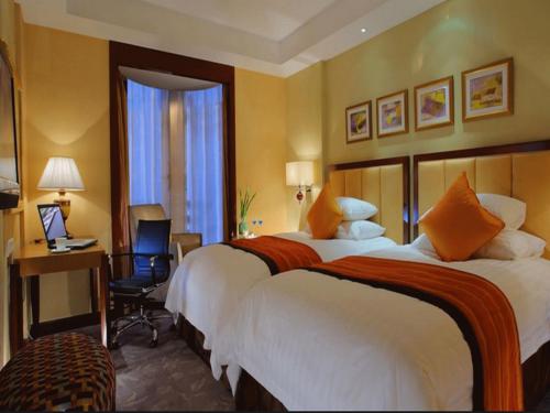 a hotel room with two beds and a desk at New Century Shaoxing Grand Hotel in Shaoxing
