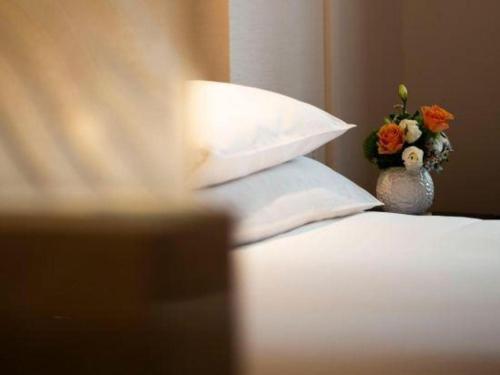 a vase of flowers sitting on top of a bed at New Century Shaoxing Grand Hotel in Shaoxing
