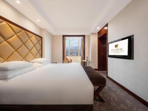 a bedroom with a large white bed and a window at New Century Shaoxing Grand Hotel in Shaoxing