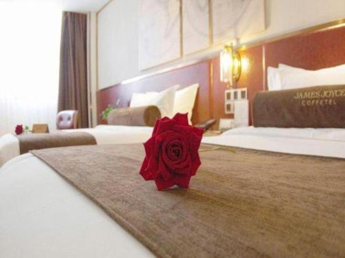 a red rose on a bed in a hotel room at James Joyce Coffetel Beijing Yizhuang Rongjing East Street Subway Station in Beijing