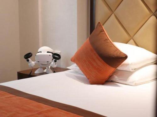 a bed with a robot on a table next to it at New Century Shaoxing Grand Hotel in Shaoxing