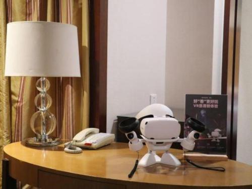 a robot on a table with a phone and a lamp at New Century Shaoxing Grand Hotel in Shaoxing