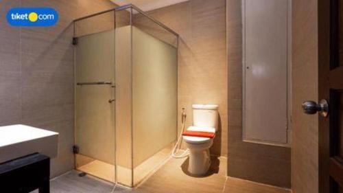a bathroom with a toilet and a glass shower at Buana Lestari Hotel in Klandasan Kecil