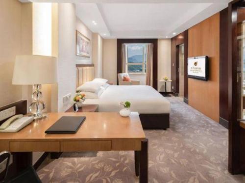 a hotel room with a bed and a desk with a desk at New Century Shaoxing Grand Hotel in Shaoxing