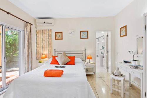 - une chambre blanche avec un grand lit et des oreillers orange dans l'établissement Villa Uma by Villa Plus, à Loulé