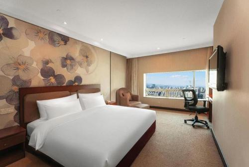 a bedroom with a large white bed and a window at Hubei Poly Hotel in Wuhan