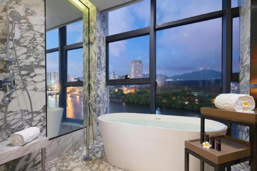 a bathroom with a bath tub and a large window at Sanya Shuangda Adelaide In Resort Hotel in Sanya