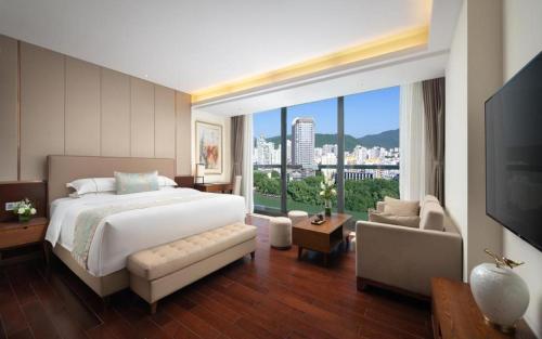 a bedroom with a large bed and a large window at Sanya Shuangda Adelaide In Resort Hotel in Sanya