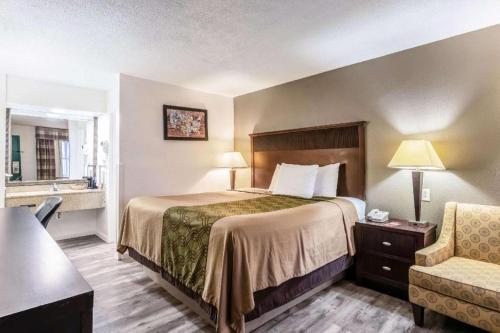 a hotel room with a bed and a chair at Econo Lodge Inn & Suites Macon North in Riverside Park