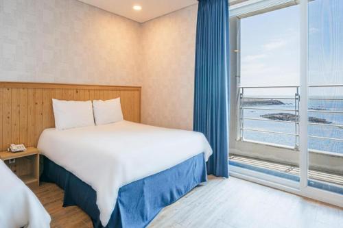 a bedroom with a bed and a large window at HOTEL52 in Seogwipo