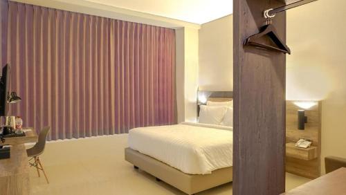 a bedroom with a bed and a red curtain at de BAGHRAF By Amithya in Sumenep