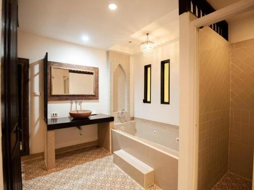 ein Badezimmer mit Badewanne, Waschbecken und Spiegel in der Unterkunft B2 Suthep Night Market Premier Resort in Chiang Mai