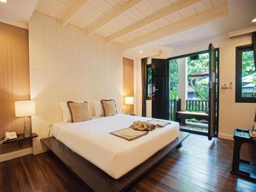 ein Schlafzimmer mit einem großen weißen Bett mit einer Handtasche darauf in der Unterkunft B2 Suthep Night Market Premier Resort in Chiang Mai