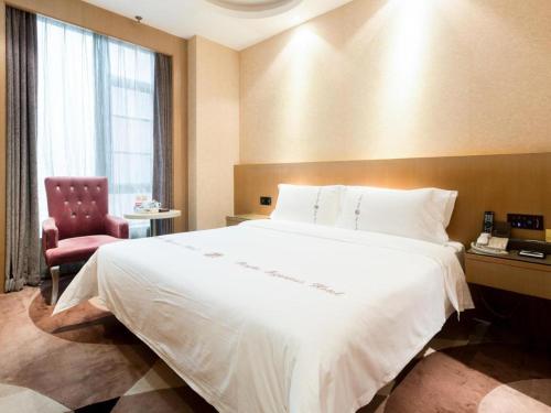 a bedroom with a large white bed and a red chair at Pengker Deluxe Collection Hotel(Haiancheng Branch) in Shenzhen