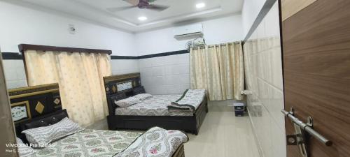 a bedroom with two beds and a ceiling fan at Sukumar Villas in Nellore