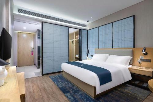 a bedroom with a large bed and a bathroom at Echarm Hotel Danzhou Xiari Plaza in Danzhou