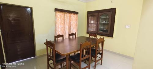 a dining room with a wooden table and chairs at Sukumar Villas in Nellore