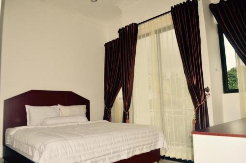 a bedroom with a bed and a large window at OPRISS HOTEL in Parapat