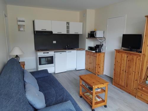 un salon avec un canapé bleu et une cuisine dans l'établissement Appartement refait à neuf en 2025, à Cabourg
