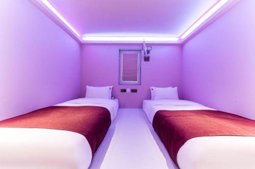 two beds in a room with purple walls at Bobo Hotel Hongdae in Seoul