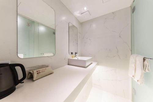 a white bathroom with a sink and a mirror at Bobo Hotel Hongdae in Seoul