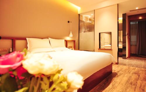 a bedroom with a large white bed with flowers at Hangzhou Berman Hotel in Hangzhou