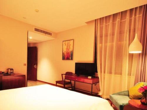 a bedroom with a bed and a couch and a television at Hangzhou Berman Hotel in Hangzhou