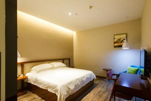 a bedroom with a white bed and a desk and a table at Hangzhou Berman Hotel in Hangzhou